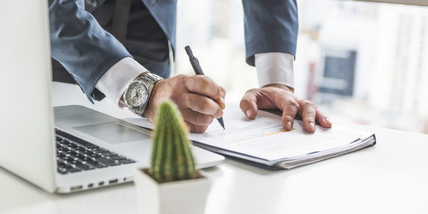 businessman-writing-document-with-pen-desk-with-laptop businessman-writing-document-with-pen-desk-with-laptop